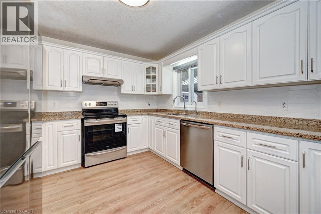 Kitchen featuring wood-finish flooring, white cabinetry, a stainless steel dishwasher, a stainless steel range, and stone countertops - 519 Yorkshire Drive, Waterloo, ON - Indoor Photo Showing Kitchen With Double Sink
