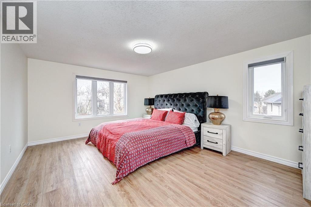 Spacious room featuring wood-finish flooring, light-colored walls, and a contemporary ceiling light fixture - 519 Yorkshire Drive, Waterloo, ON - Indoor Photo Showing Bedroom