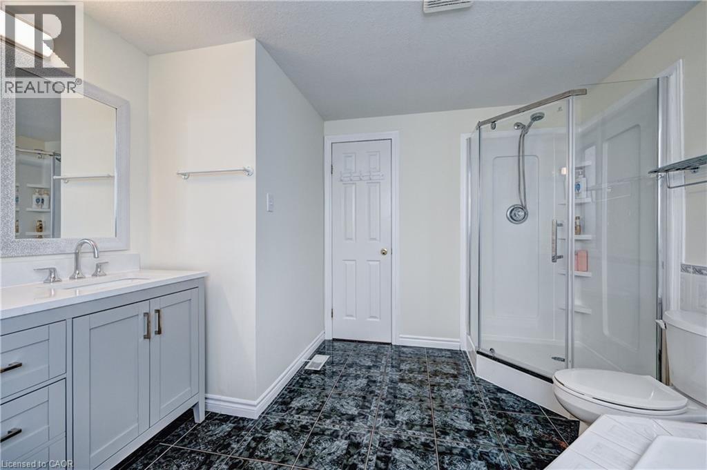 Bathroom featuring a glass-enclosed shower, a vanity with light gray cabinetry and a white countertop, and dark patterned floor tiles - 519 Yorkshire Drive, Waterloo, ON - Indoor Photo Showing Bathroom