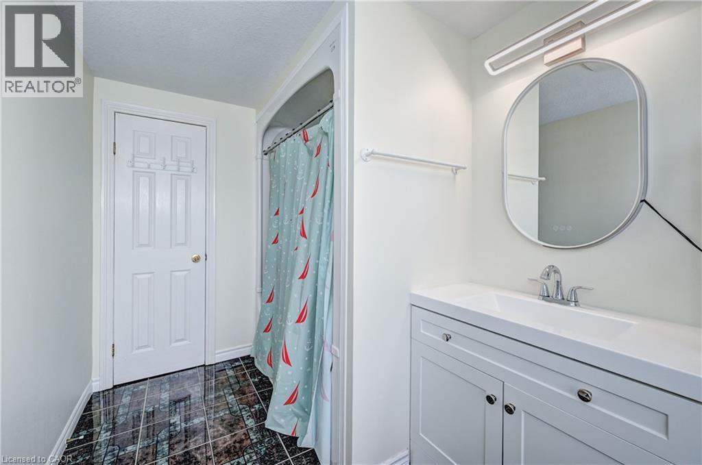 Bathroom featuring a contemporary vanity with an integrated sink, polished chrome faucet, and an oval-framed mirror with integrated lighting - 519 Yorkshire Drive, Waterloo, ON - Indoor Photo Showing Bathroom