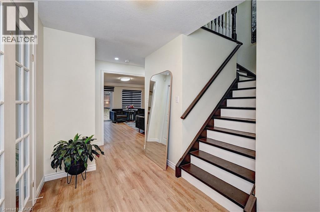 Entryway featuring wood-finish flooring, a dark wood staircase with white risers, and a prominent archway leading to a rear living space - 519 Yorkshire Drive, Waterloo, ON - Indoor Photo Showing Other Room