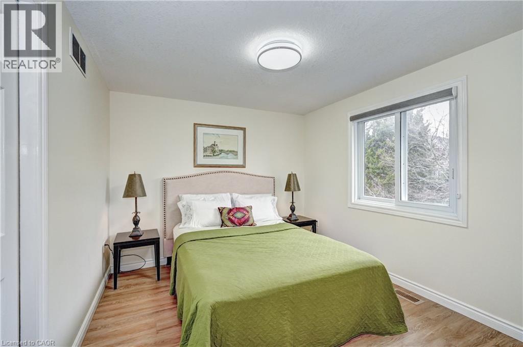 Bedroom featuring wood-finish flooring, a contemporary ceiling light fixture, a large sliding window, and neutral wall paint - 519 Yorkshire Drive, Waterloo, ON - Indoor Photo Showing Bedroom