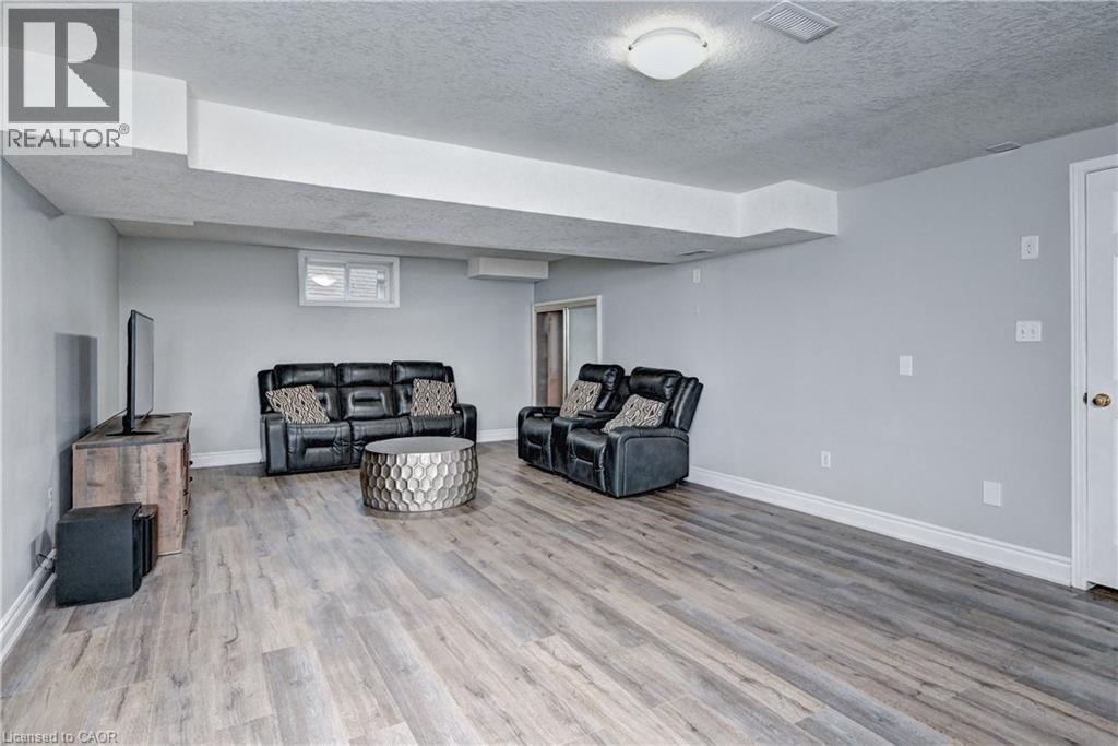 Spacious recreation room featuring light gray walls, white baseboards, and wood-finish flooring - 519 Yorkshire Drive, Waterloo, ON - Indoor