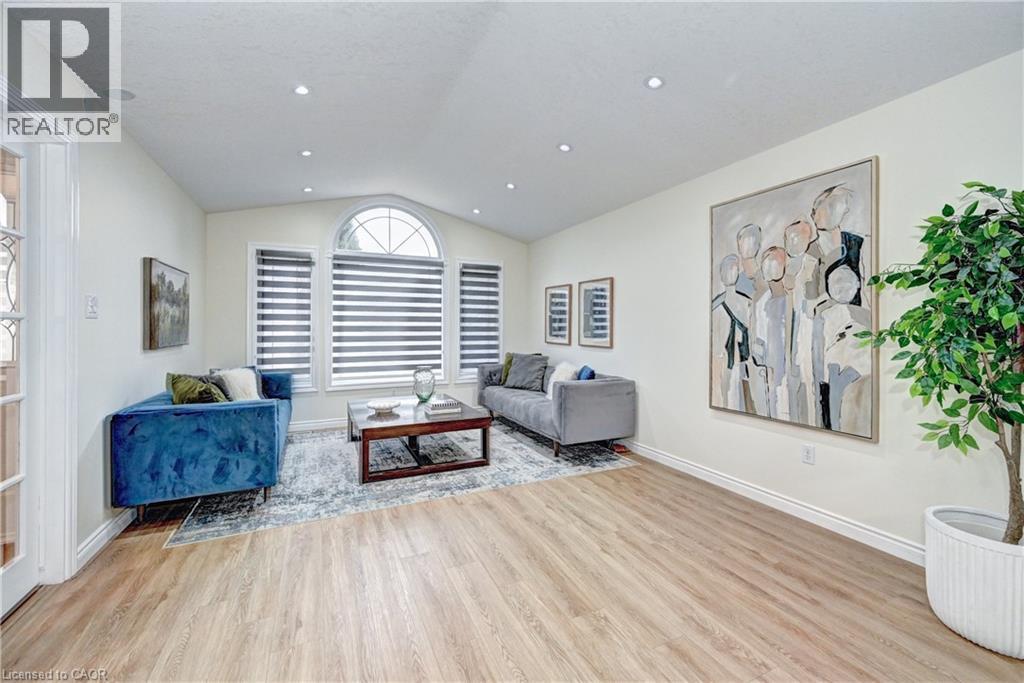 Spacious living area featuring wood-finish flooring, recessed lighting, and a vaulted ceiling with an arched window - 519 Yorkshire Drive, Waterloo, ON - Indoor