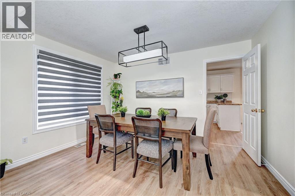 Dining area featuring wood-finish flooring, a contemporary rectangular chandelier, and a large window with horizontal blinds - 519 Yorkshire Drive, Waterloo, ON - Indoor Photo Showing Dining Room