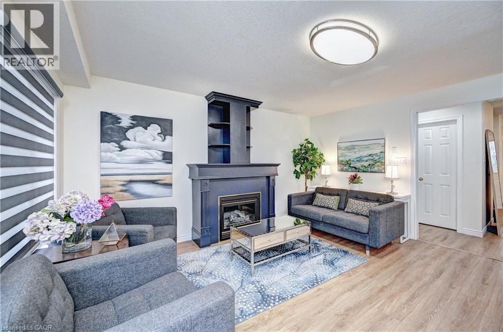 Living area featuring a fireplace with a dark mantel and built-in shelving, wood-finish flooring, and a flush-mount ceiling light - 519 Yorkshire Drive, Waterloo, ON - Indoor Photo Showing Living Room With Fireplace