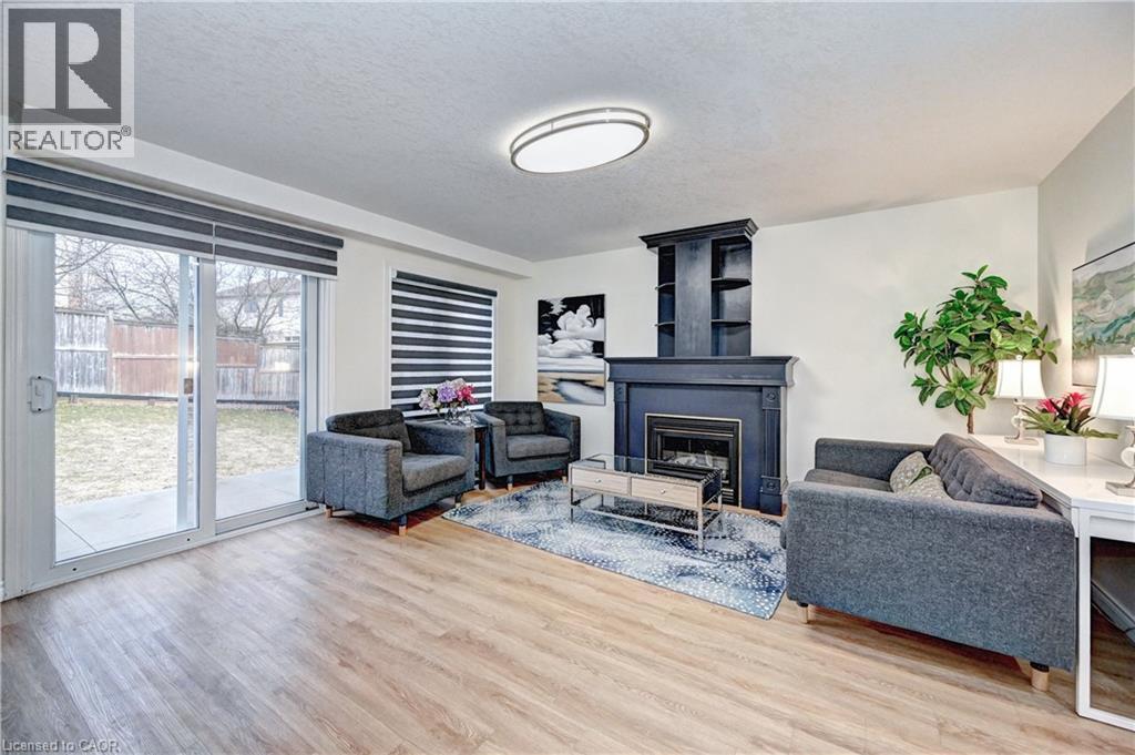 Living area featuring wood-finish flooring, a fireplace with built-in shelving, and sliding glass doors to the exterior - 519 Yorkshire Drive, Waterloo, ON - Indoor Photo Showing Living Room With Fireplace