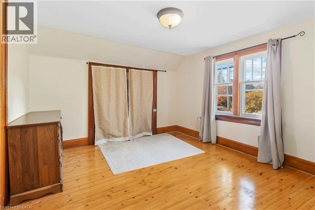 Room featuring wood-finish flooring, two large windows with natural wood trim, a flush-mount ceiling light fixture, and light-toned wall paint - 151 Louisa Street, Kitchener, ON - Indoor Photo Showing Other Room