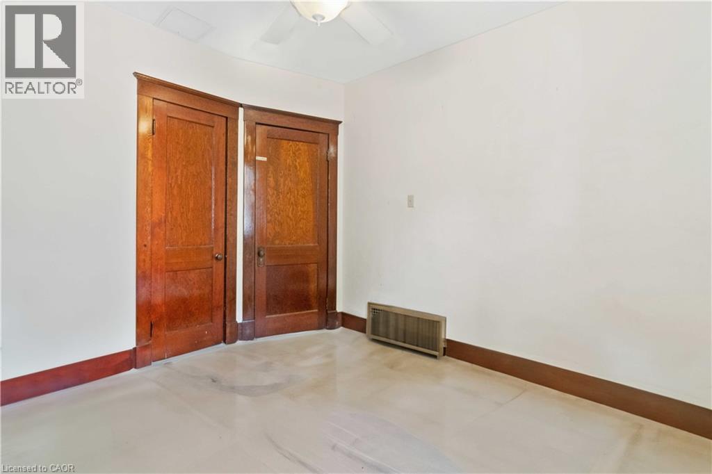 Interior room featuring two paneled wood doors with matching trim, light-toned flooring, and a ceiling fan - 151 Louisa Street, Kitchener, ON - Indoor