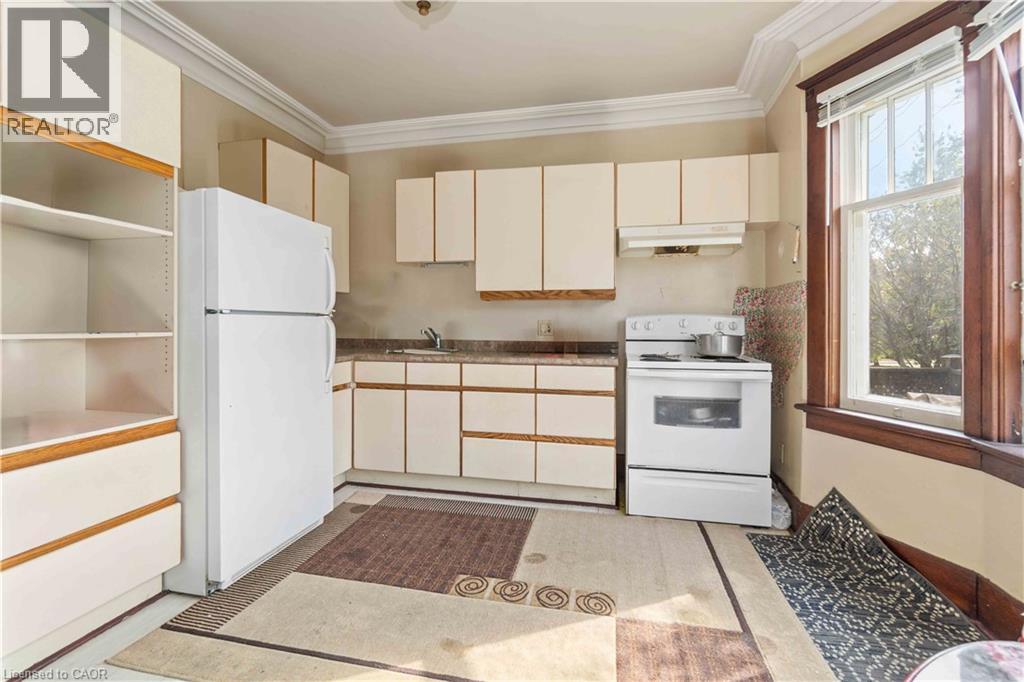 Kitchen featuring white cabinetry with wood-tone accents, a freestanding white refrigerator, and a white electric range with overhead ventilation - 151 Louisa Street, Kitchener, ON - Indoor Photo Showing Kitchen
