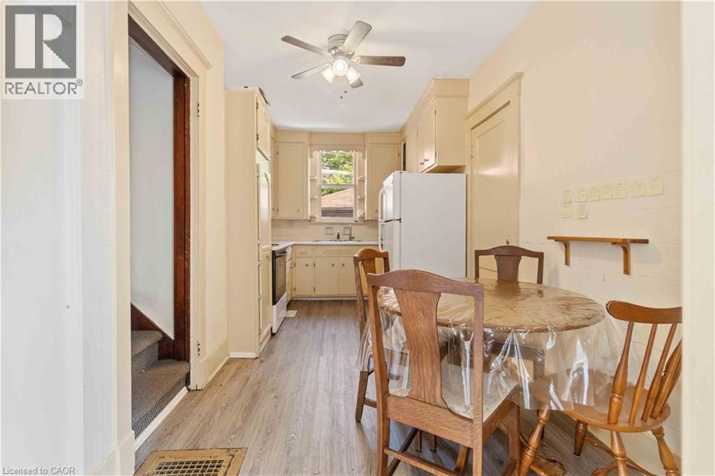 Compact kitchen featuring wood-finish flooring, cream-colored cabinetry, a white refrigerator, and a ceiling fan with integrated lighting - 151 Louisa Street, Kitchener, ON - Indoor Photo Showing Dining Room