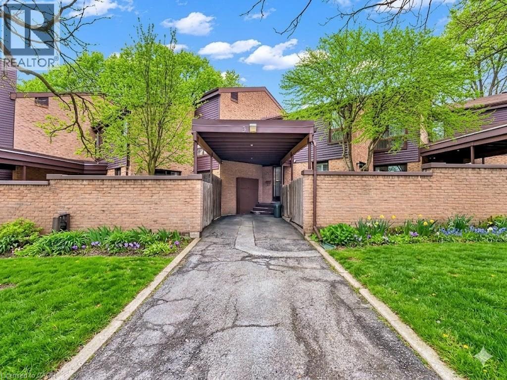 Brick exterior with a covered carport entrance, surrounded by established landscaping and mature trees - 28 Underhill Crescent Unit# 3, Kitchener, ON - Outdoor