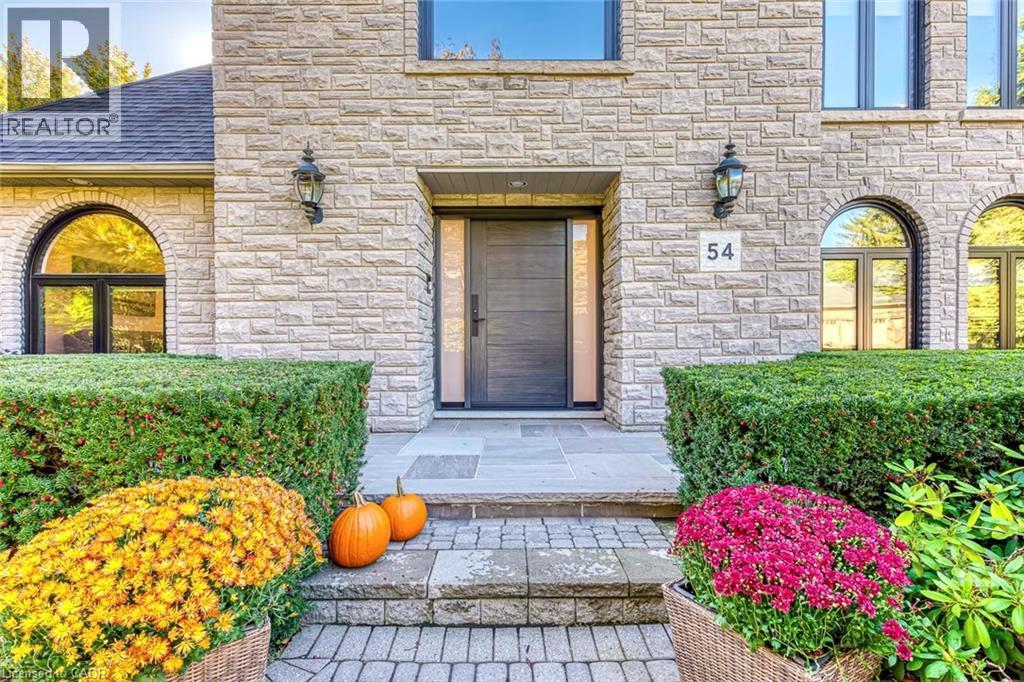 Stone facade with arched windows, prominent front entry door, and decorative wall lanterns - 54 Deerview Avenue, Ancaster, ON - Outdoor