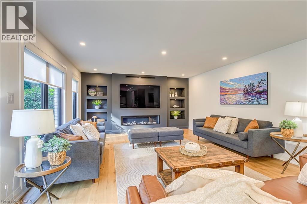 Living area featuring a recessed fireplace with built-in shelving, wood-finish flooring, recessed lighting, and large windows - 54 Deerview Avenue, Ancaster, ON - Indoor Photo Showing Living Room