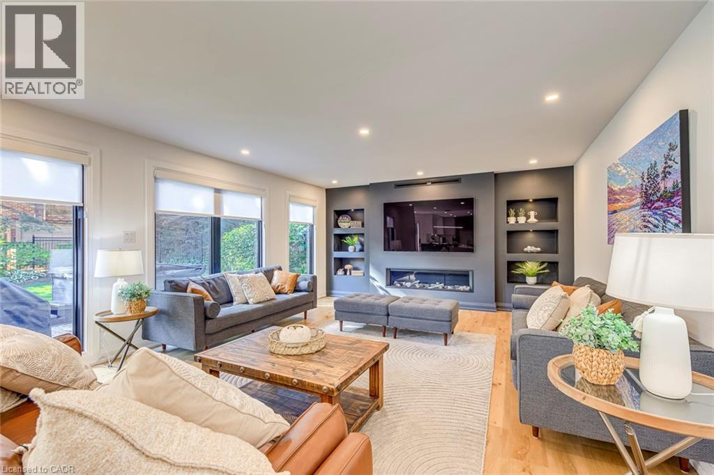Living area featuring wood-finish flooring, recessed lighting, and large windows with roller shades - 54 Deerview Avenue, Ancaster, ON - Indoor Photo Showing Living Room