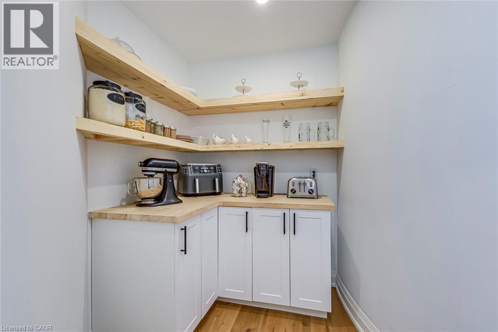 Corner pantry featuring white cabinetry with matte black hardware, light wood-finish countertops, and open wood-finish shelving - 54 Deerview Avenue, Ancaster, ON - Indoor Photo Showing Kitchen