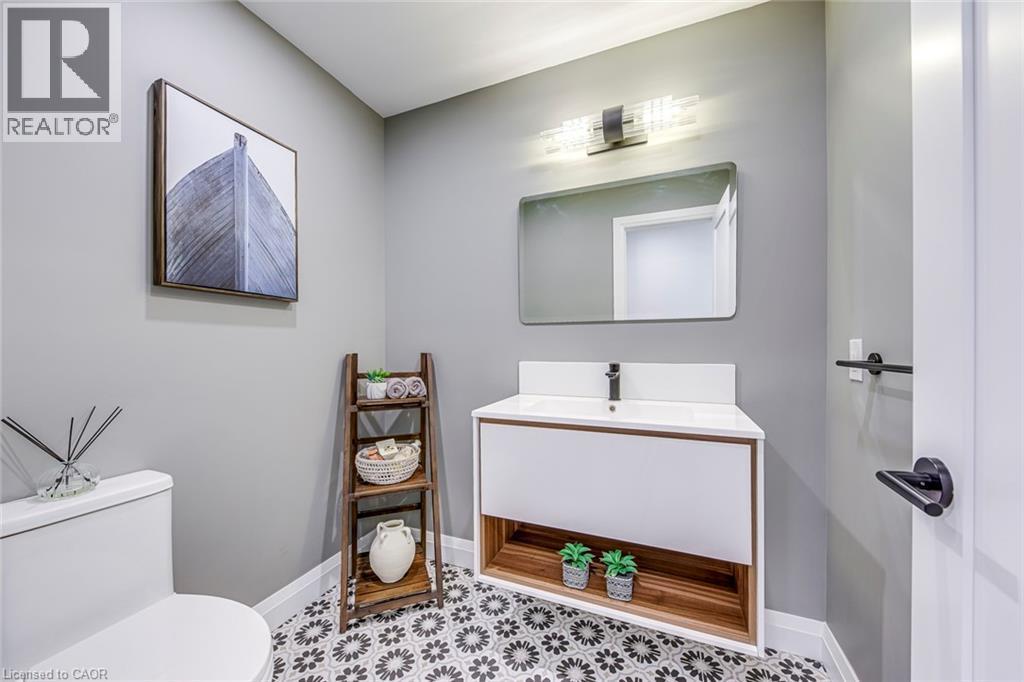 Modern bathroom featuring patterned floor tiles, a floating vanity with integrated sink, and a sleek rectangular mirror - 54 Deerview Avenue, Ancaster, ON - Indoor Photo Showing Bathroom