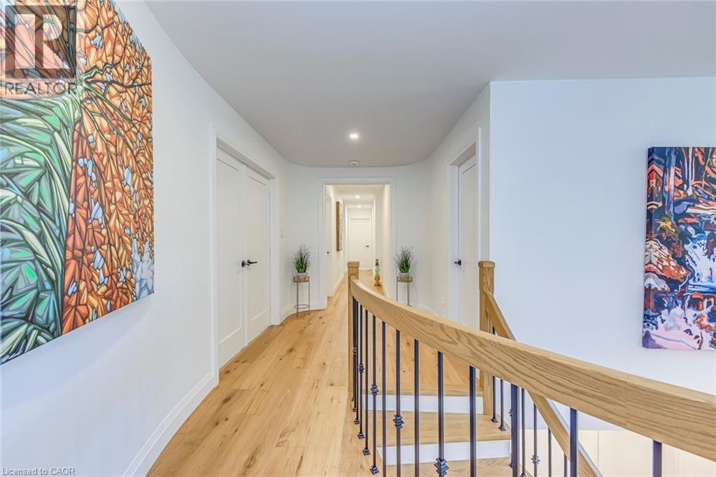 Hallway featuring wood-finish flooring, recessed lighting, and white paneled doors with black hardware - 54 Deerview Avenue, Ancaster, ON - Indoor Photo Showing Other Room