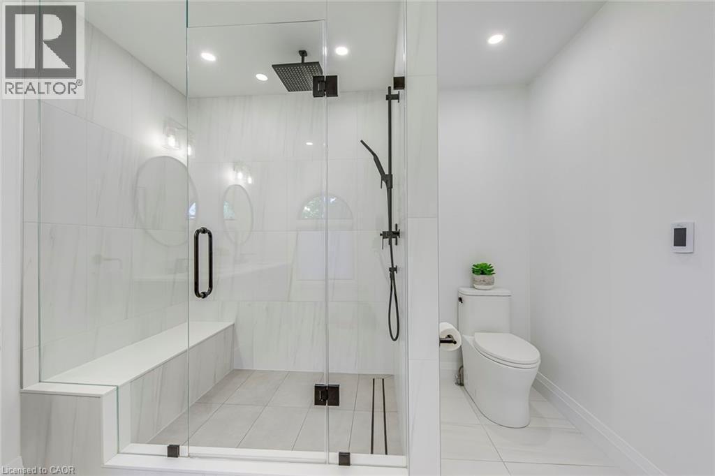 Glass-enclosed shower featuring a built-in bench, black matte fixtures, and recessed lighting - 54 Deerview Avenue, Ancaster, ON - Indoor Photo Showing Bathroom