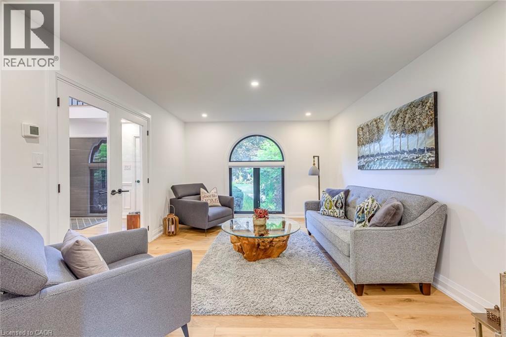 Recessed lighting illuminates this bright room featuring light wood-finish flooring and a distinctive arched window - 54 Deerview Avenue, Ancaster, ON - Indoor Photo Showing Living Room