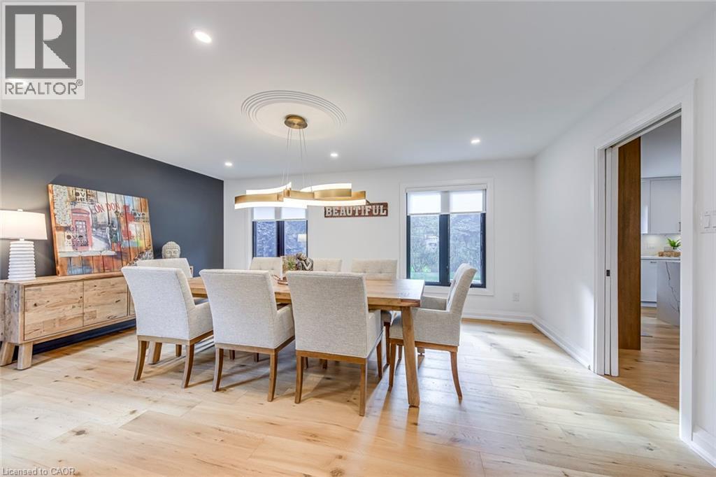 Dining area featuring wide plank wood-finish flooring, recessed lighting, and a contemporary chandelier - 54 Deerview Avenue, Ancaster, ON - Indoor Photo Showing Dining Room