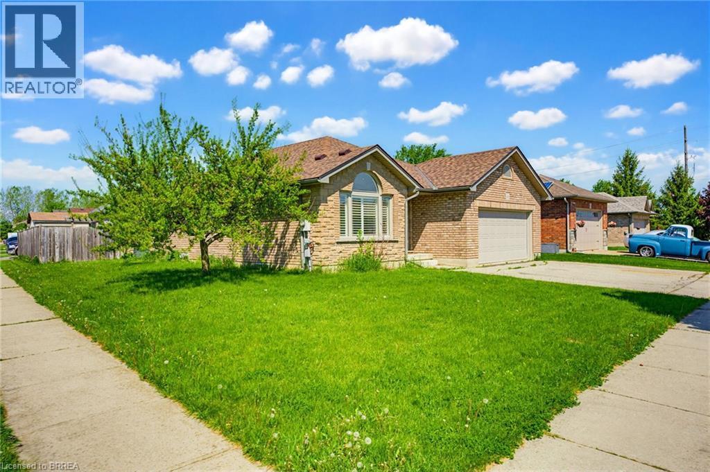 Brick facade residence featuring an attached garage, a front lawn, a mature tree, and a concrete sidewalk - 6 General Street, Brantford, ON - Outdoor