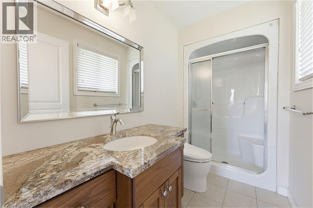 Bathroom featuring a vanity with a light-colored, patterned countertop, an undermount sink, and a framed mirror - 6 General Street, Brantford, ON - Indoor Photo Showing Bathroom