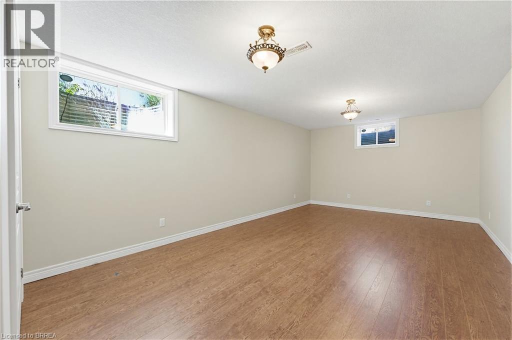 Expansive room featuring wood-finish flooring, light-toned wall paint, white trim, and two windows - 6 General Street, Brantford, ON - Indoor Photo Showing Other Room