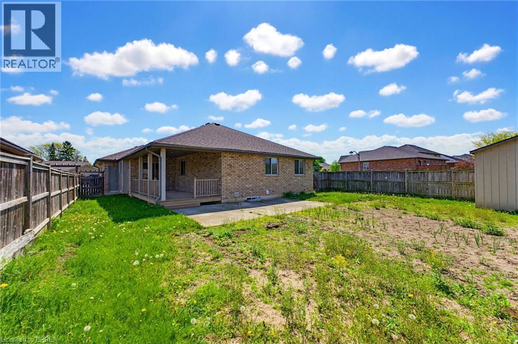 Expansive backyard featuring a partial grass lawn, a covered patio with wood deck and railing, and a privacy fence - 6 General Street, Brantford, ON - Outdoor With Backyard