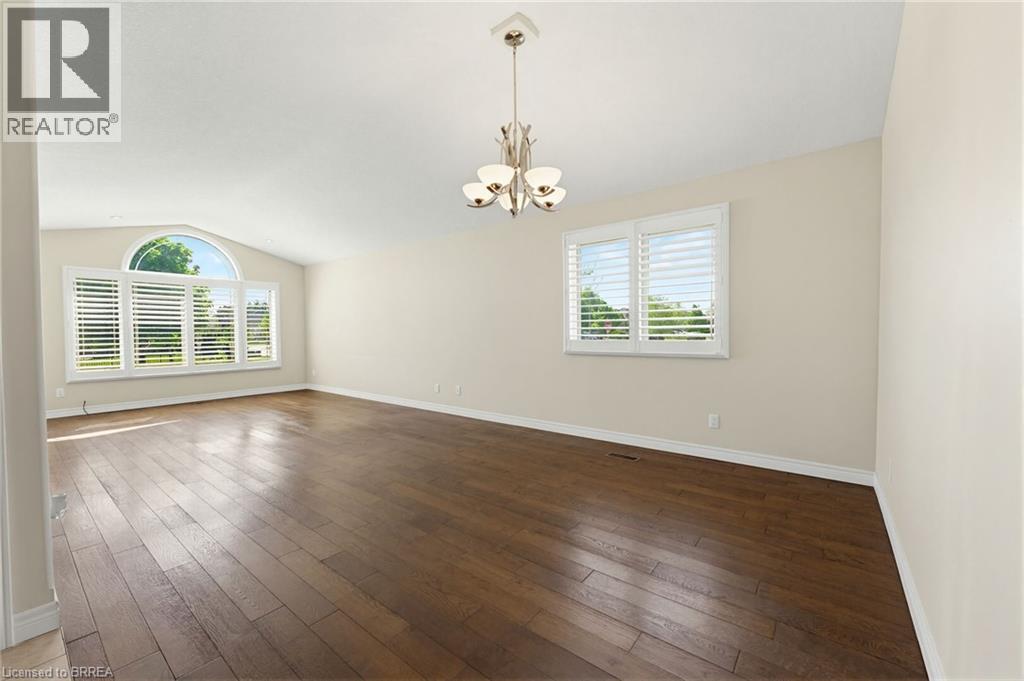 Spacious room featuring rich wood-finish flooring, vaulted ceilings, and a contemporary chandelier - 6 General Street, Brantford, ON - Indoor Photo Showing Other Room