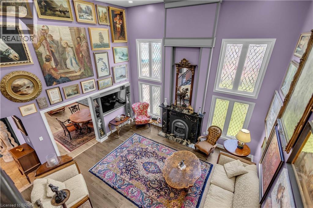 Two-story living area with wood-finish flooring, a black marble fireplace, and multiple tall, diamond-pane windows - 69 Hunter Way, Brantford, ON - Indoor With Fireplace