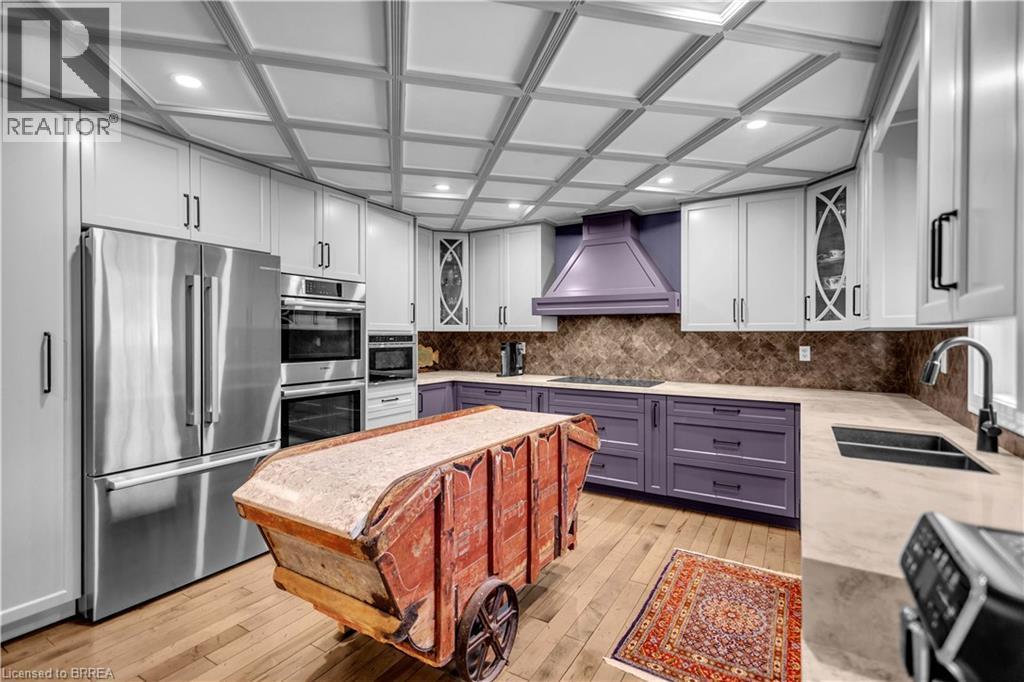 Contemporary kitchen featuring a coffered ceiling with recessed lighting, stainless steel appliances, light-toned countertops, and a patterned backsplash - 69 Hunter Way, Brantford, ON - Indoor Photo Showing Kitchen With Double Sink With Upgraded Kitchen