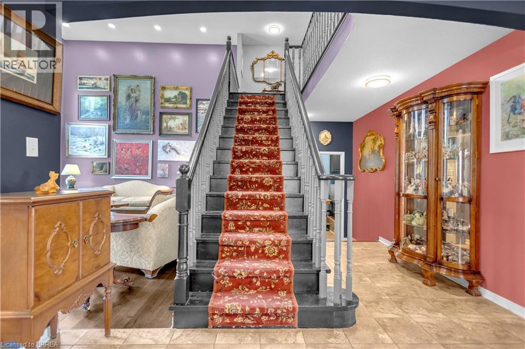Grand staircase featuring a patterned runner and dark-stained banister - 69 Hunter Way, Brantford, ON - Indoor Photo Showing Other Room