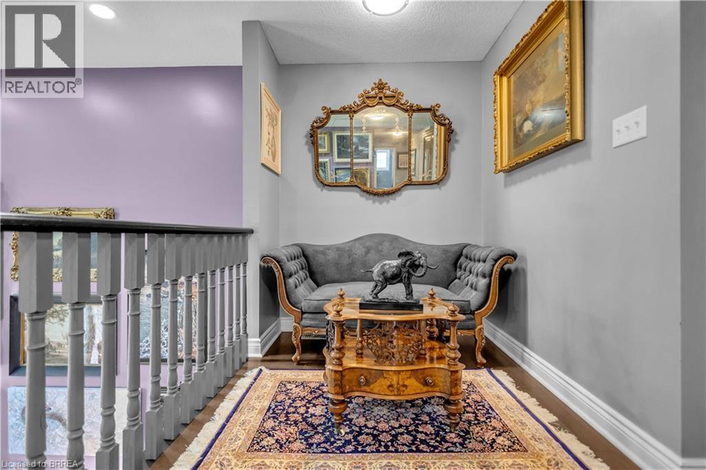 Hardwood flooring in a hallway alcove featuring a decorative area rug, chair rail molding, and a balustrade - 69 Hunter Way, Brantford, ON - Indoor Photo Showing Other Room