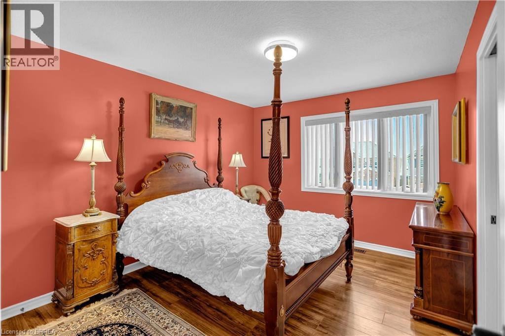 Spacious room featuring wood-finish flooring, a contemporary ceiling light fixture, and a window with vertical blinds - 69 Hunter Way, Brantford, ON - Indoor Photo Showing Bedroom