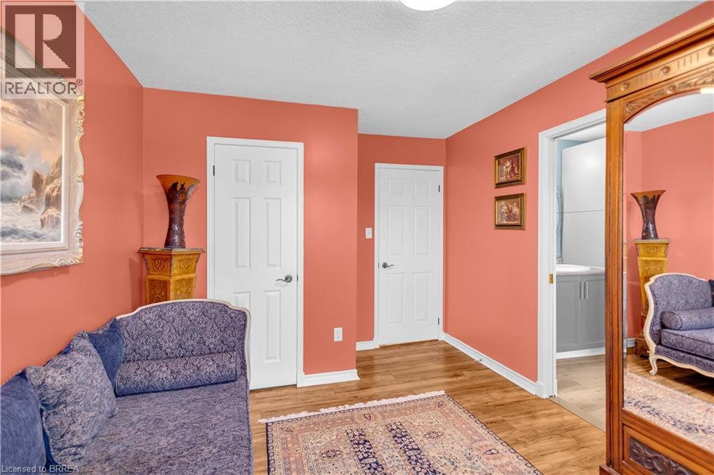 Interior hallway with wood-finish flooring, two panel doors, and a bathroom entrance featuring a vanity with a sink - 69 Hunter Way, Brantford, ON - Indoor