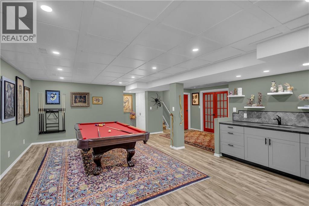 Expansive recreation room featuring wood-finish flooring, recessed lighting, and a built-in wet bar with gray cabinetry and a dark countertop - 69 Hunter Way, Brantford, ON - Indoor Photo Showing Other Room