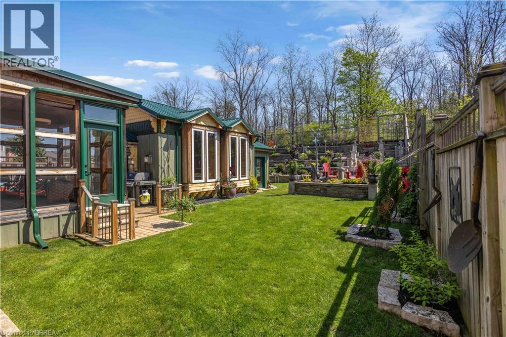 Expansive green lawn providing a contrast to the natural wood siding and green metal roofing - 69 Hunter Way, Brantford, ON - Outdoor