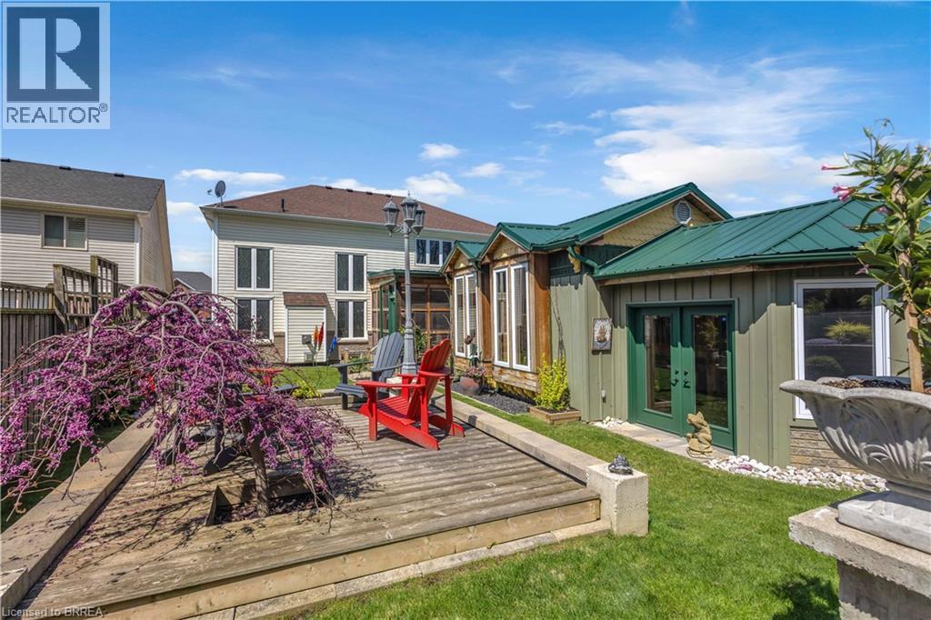 Backyard features a multi-level wooden deck, mature flowering tree, and manicured lawn - 69 Hunter Way, Brantford, ON - Outdoor