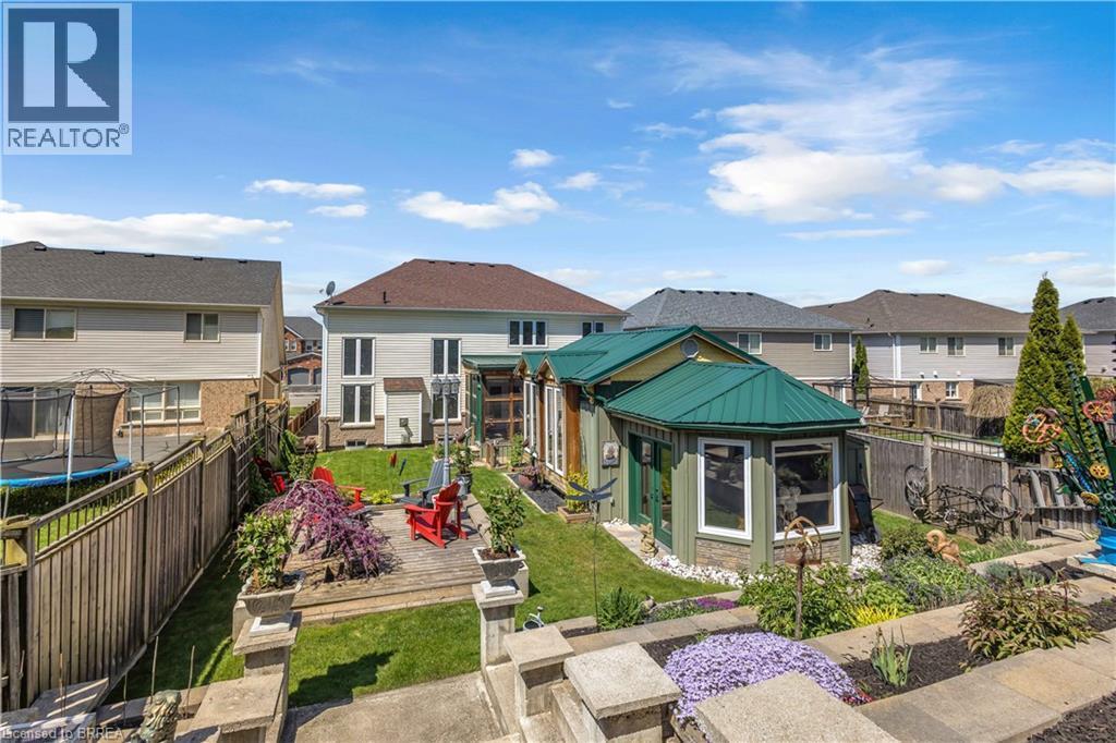 Expansive backyard featuring a green-roofed garden structure, a wooden deck, manicured lawn, and tiered landscaping - 69 Hunter Way, Brantford, ON - Outdoor