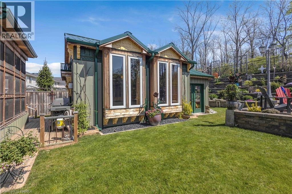 Expansive green lawn featuring a stone retaining wall and a terraced garden with established plantings - 69 Hunter Way, Brantford, ON - Outdoor
