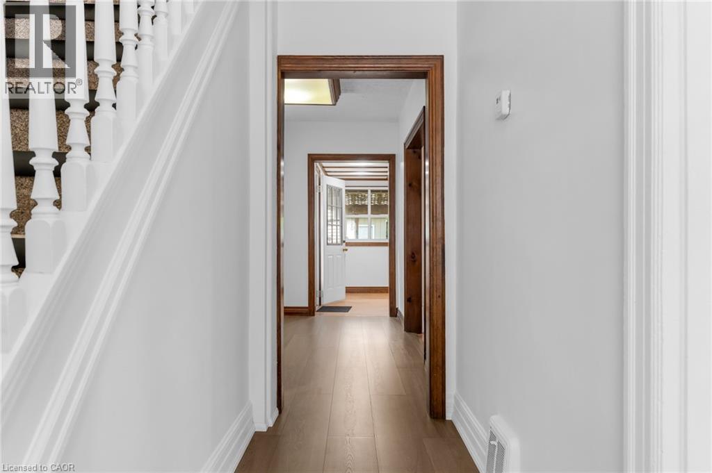 Hallway featuring light wood-finish flooring, white painted walls, and warm wood door frames - 168 Britannia Avenue, Hamilton, ON - Indoor Photo Showing Other Room