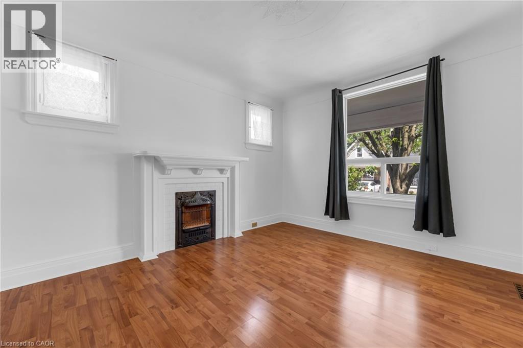 Bright living space featuring warm wood-finish flooring - 168 Britannia Avenue, Hamilton, ON - Indoor With Fireplace