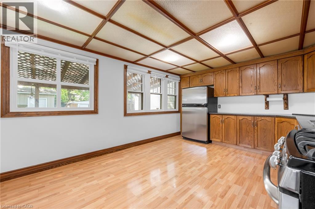 Kitchen space featuring wood-finish flooring, two windows with white blinds, and a paneled ceiling - 168 Britannia Avenue, Hamilton, ON - Indoor