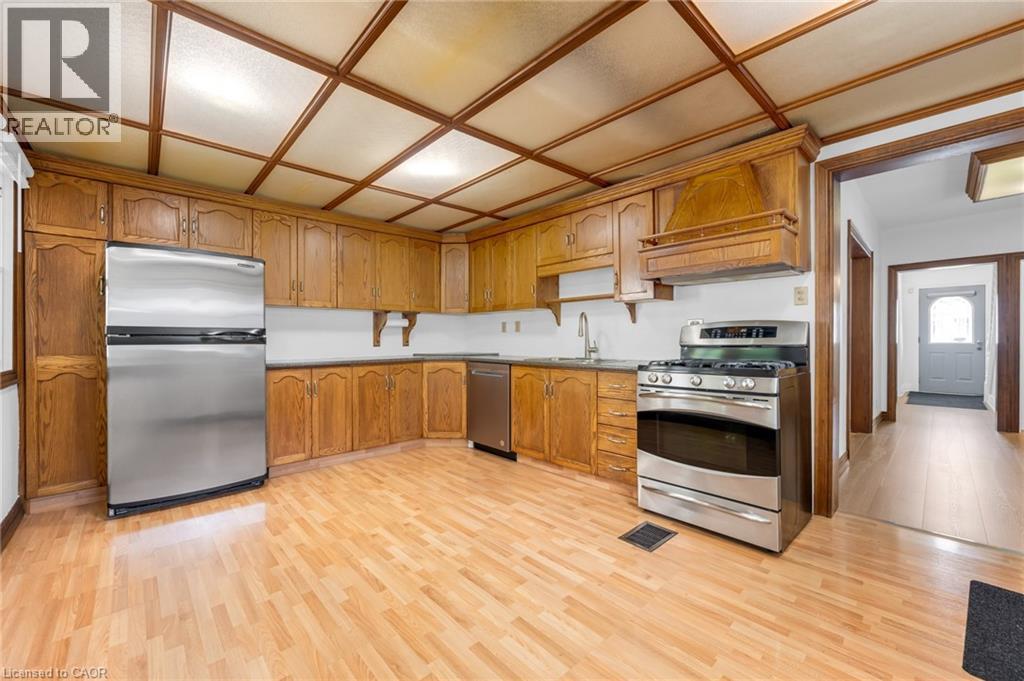 Kitchen featuring wood-finish flooring, extensive wood cabinetry, stainless steel appliances, and a coffered ceiling - 168 Britannia Avenue, Hamilton, ON - Indoor Photo Showing Kitchen