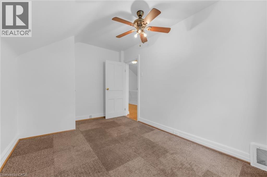 Room featuring neutral wall finishes, a ceiling-mounted fan with integrated lighting, and brown carpet tile flooring - 168 Britannia Avenue, Hamilton, ON - Indoor Photo Showing Other Room