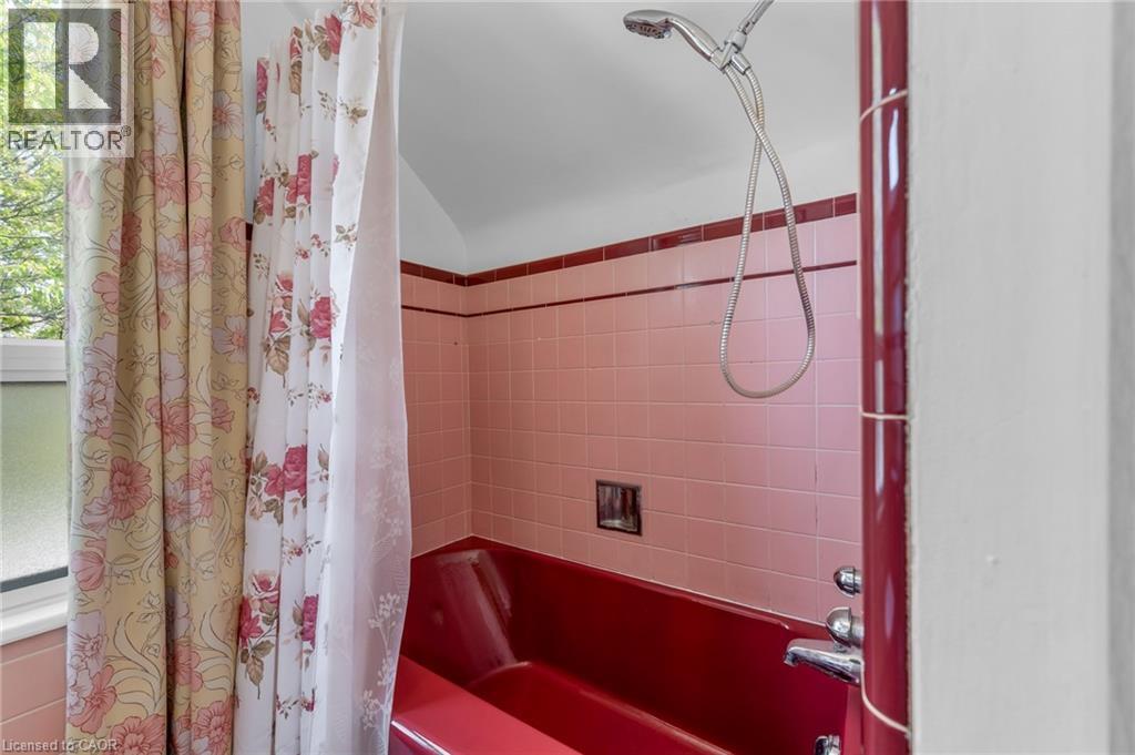 Pink tile surround with contrasting dark red accent trim and a red bathtub - 168 Britannia Avenue, Hamilton, ON - Indoor Photo Showing Bathroom