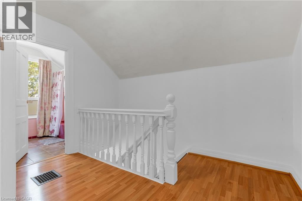 Hallway featuring wood-finish flooring, a white spindle staircase railing, and white wall finishes - 168 Britannia Avenue, Hamilton, ON - Indoor Photo Showing Other Room