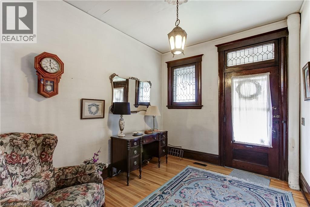 Entryway featuring a rich wood-finish door with leaded glass transom and side window, hardwood flooring, and a pendant light fixture - 18 Fairleigh Crescent, Hamilton, ON - Indoor