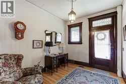 Entryway featuring a rich wood-finish door with leaded glass transom and side window, hardwood flooring, and a pendant light fixture -